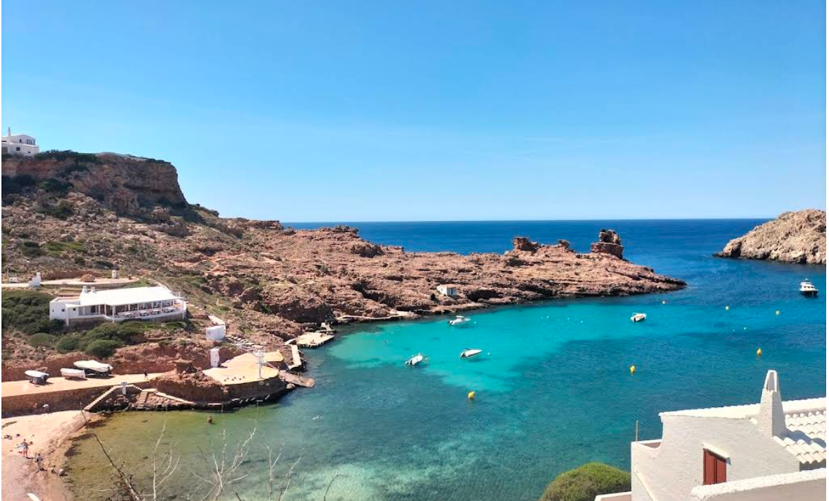 Cala Morell, a rocky inlet with turquoise water and whitewashed houses on the cliffs