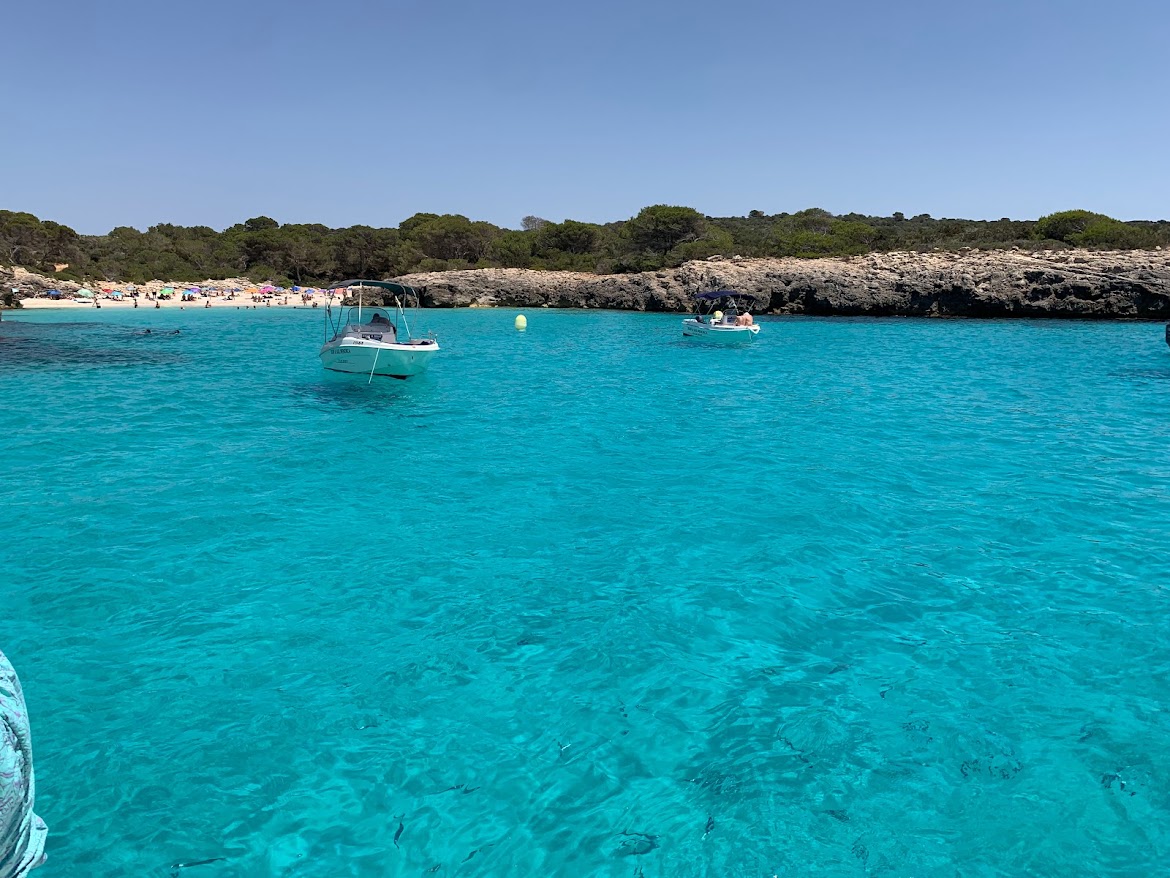 Small boats anchored in a clear turquoise bay near a beach