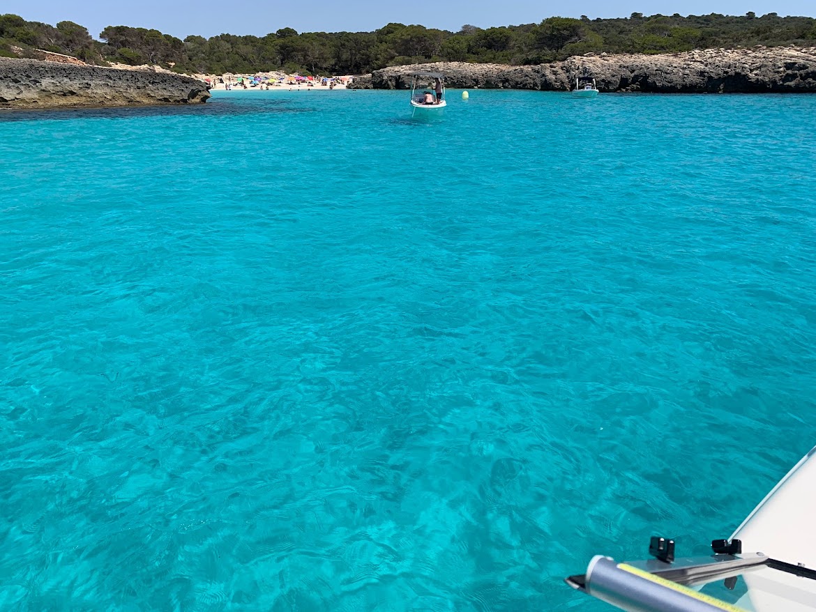 View across turquoise water toward the cove and anchored boats