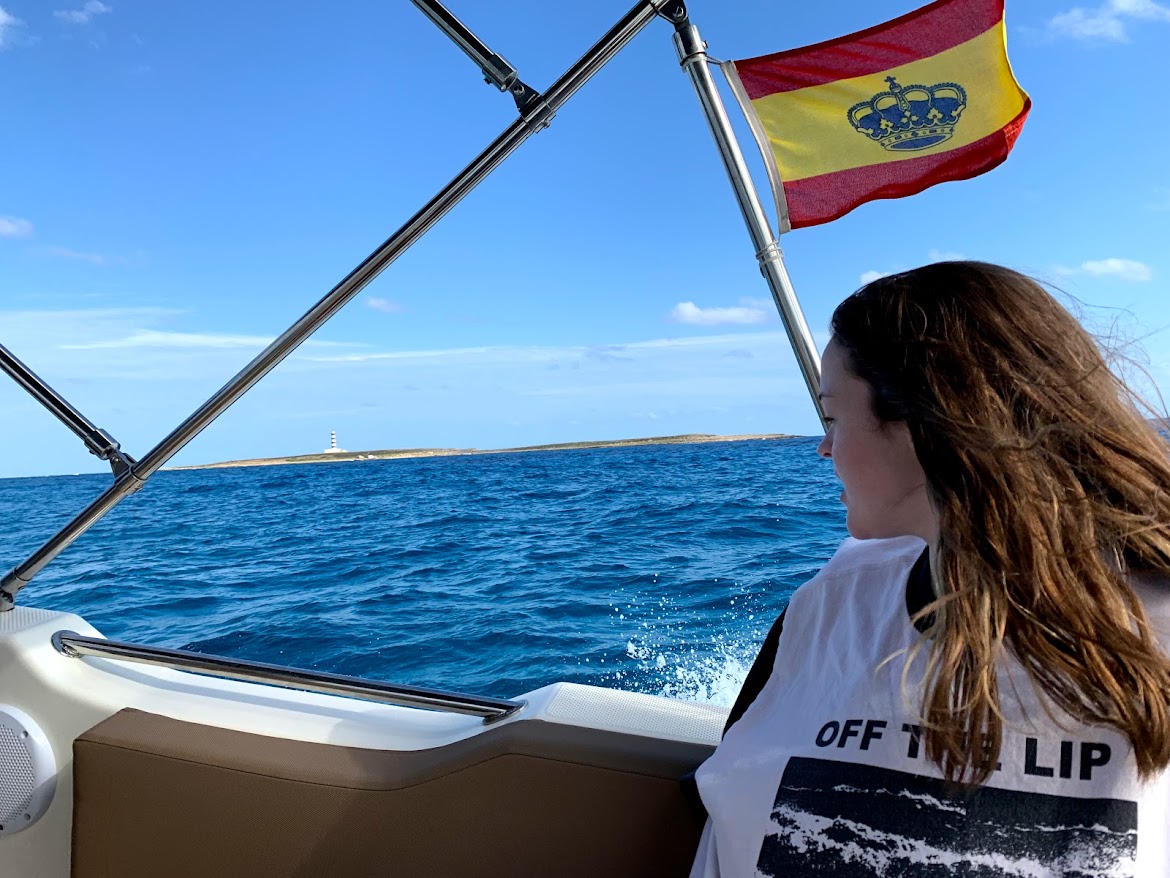 Woman watching the coastline from the boat under the Spanish flag