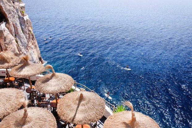 Cova d'en Xoroi's thatched umbrellas above the cliff, sea below