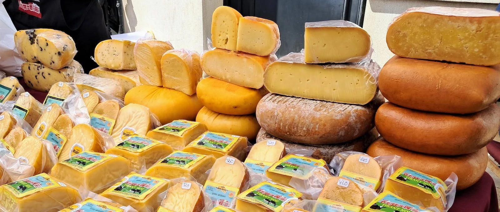 Wheels and blocks of Mahón cheese at a market stall