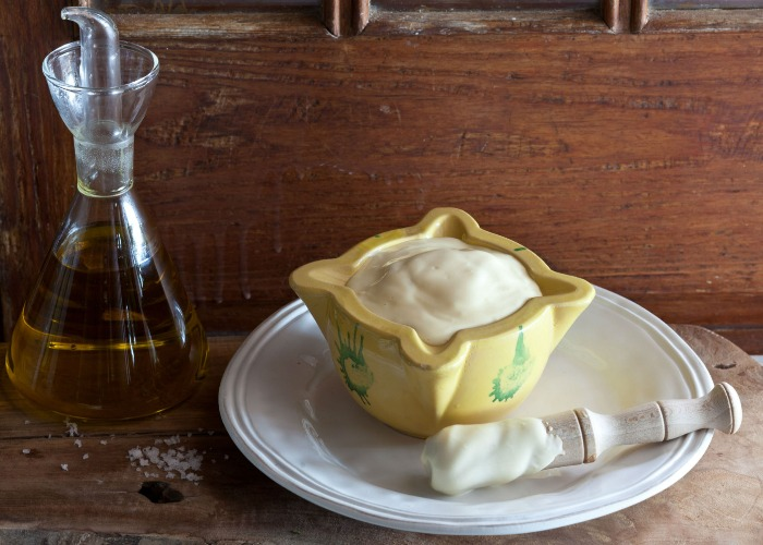 A bowl of mayonnaise with olive oil beside it