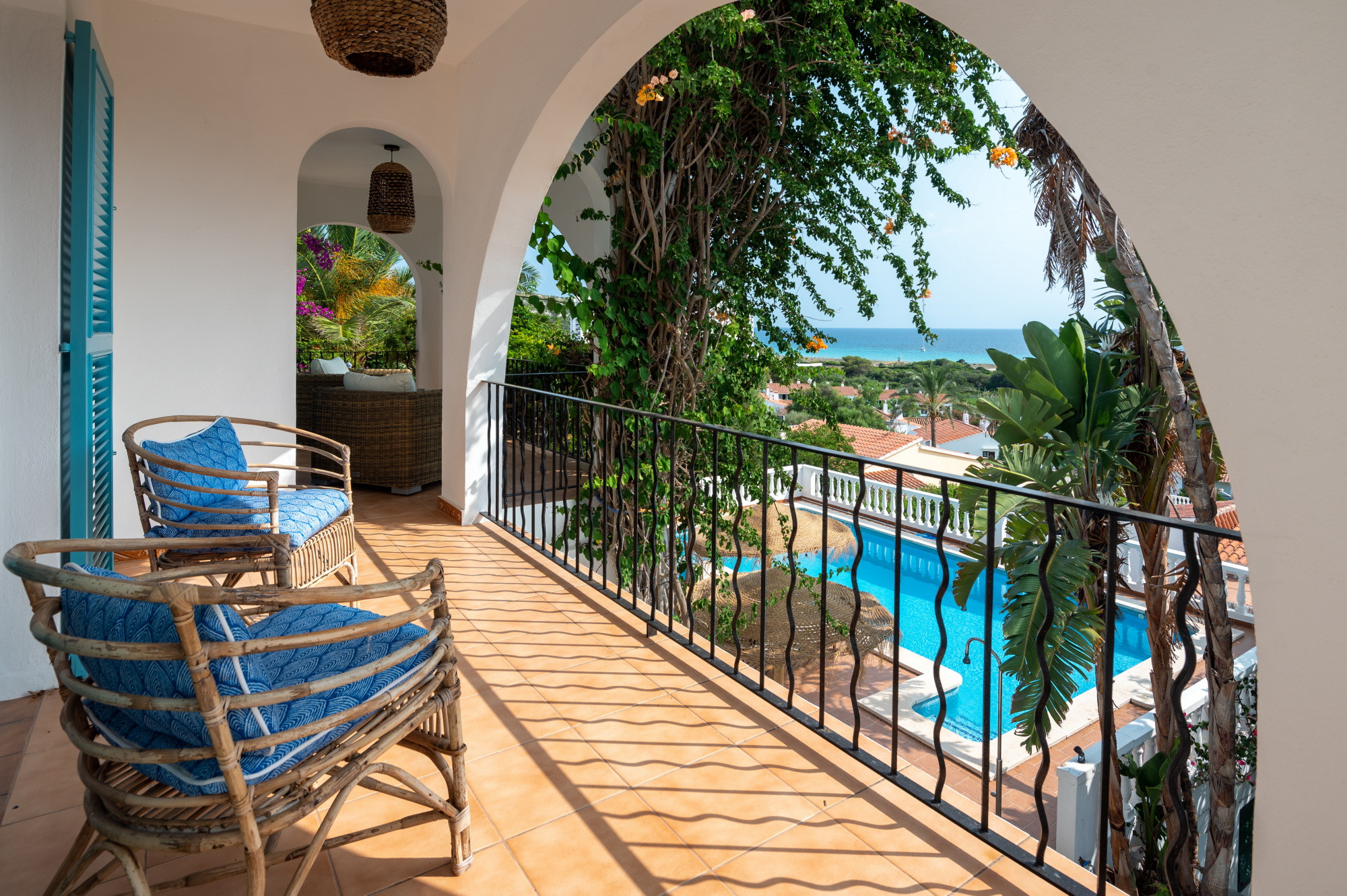 Villa balcony with rattan chairs overlooking the pool and sea