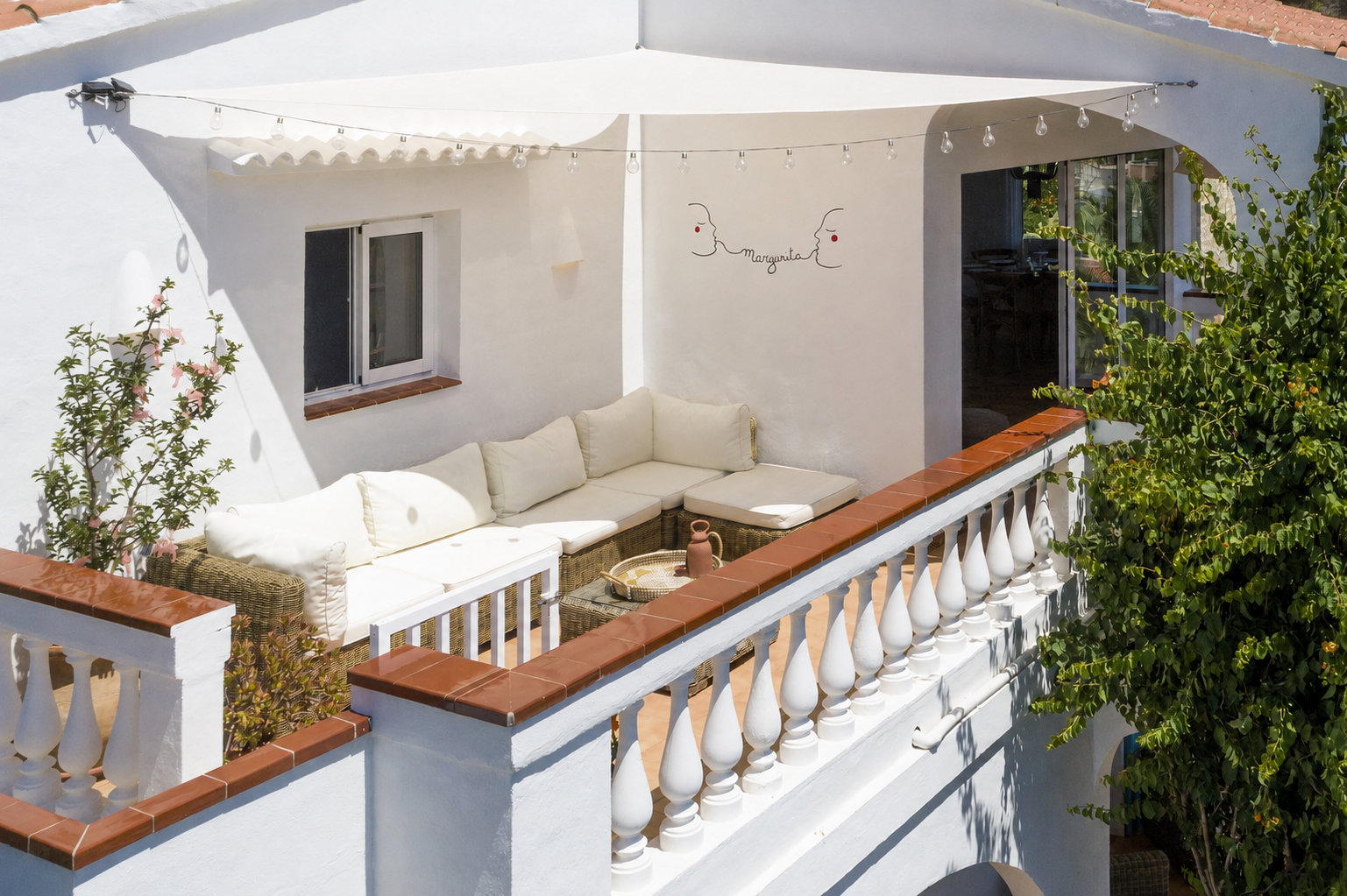 Shaded balcony terrace with rattan sofa and string lights