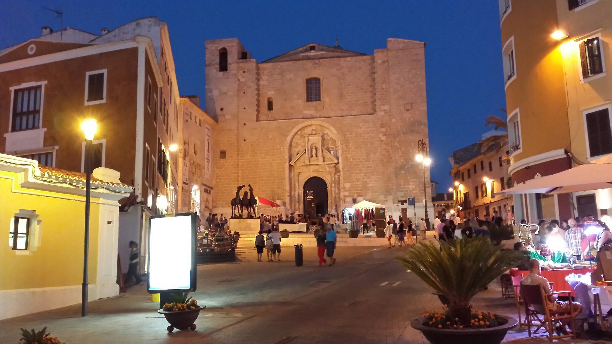 Maó's old church square lit up at dusk with market stalls