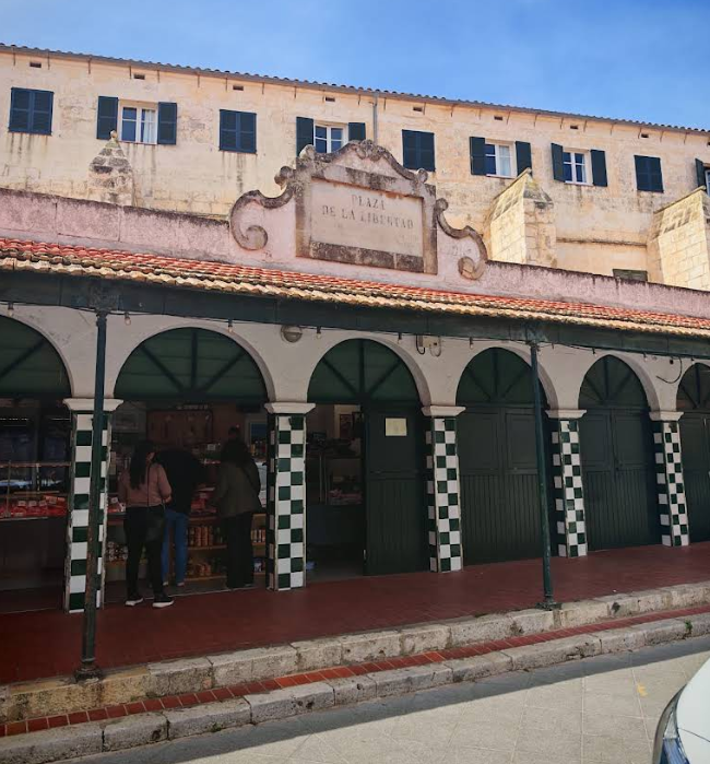 The arcaded green-and-white facade of Ciutadella's Mercat Municipal on Plaça de la Llibertat