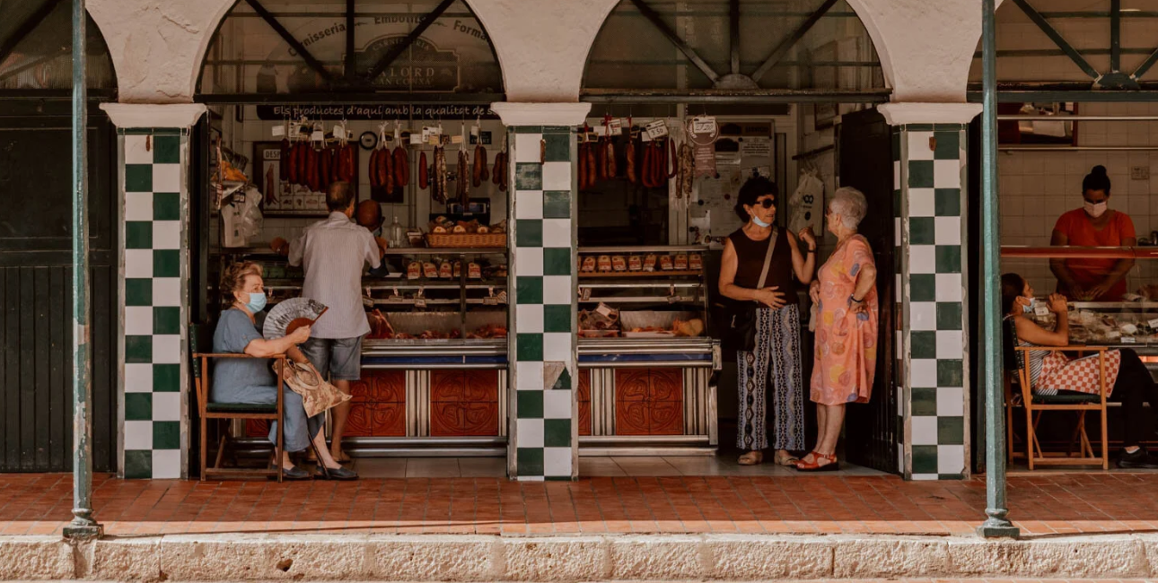 Shoppers at the market's butcher and charcuterie counters under the arches