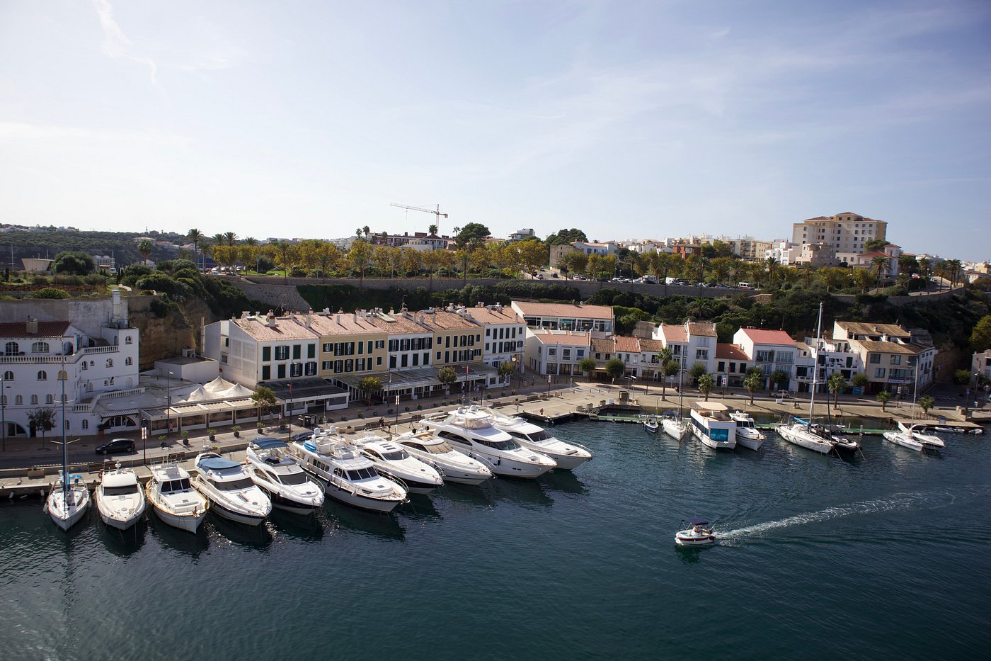 Yachts moored along Maó's marina with the old town above